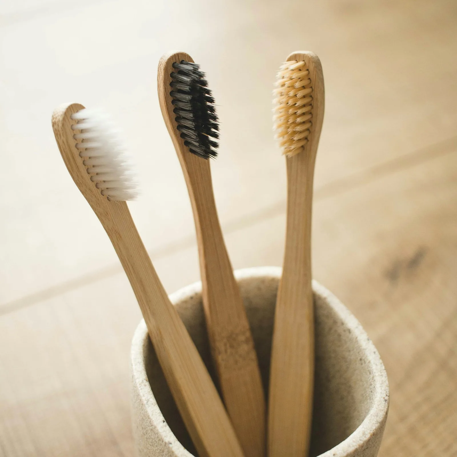 Three bamboo toothbrushes standing in a ceramic cup